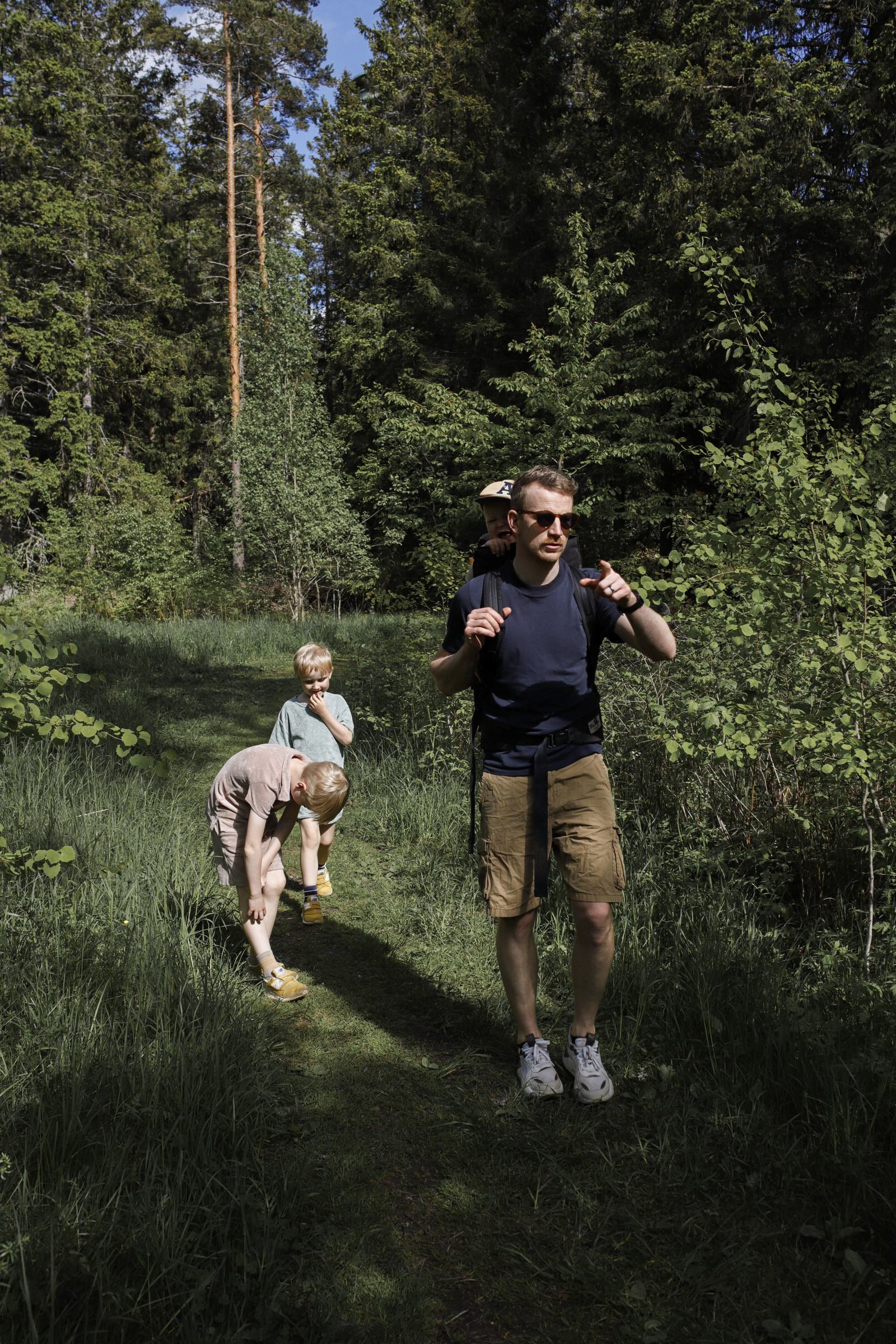 Linnéas man och barn vandrar i skogen. 
