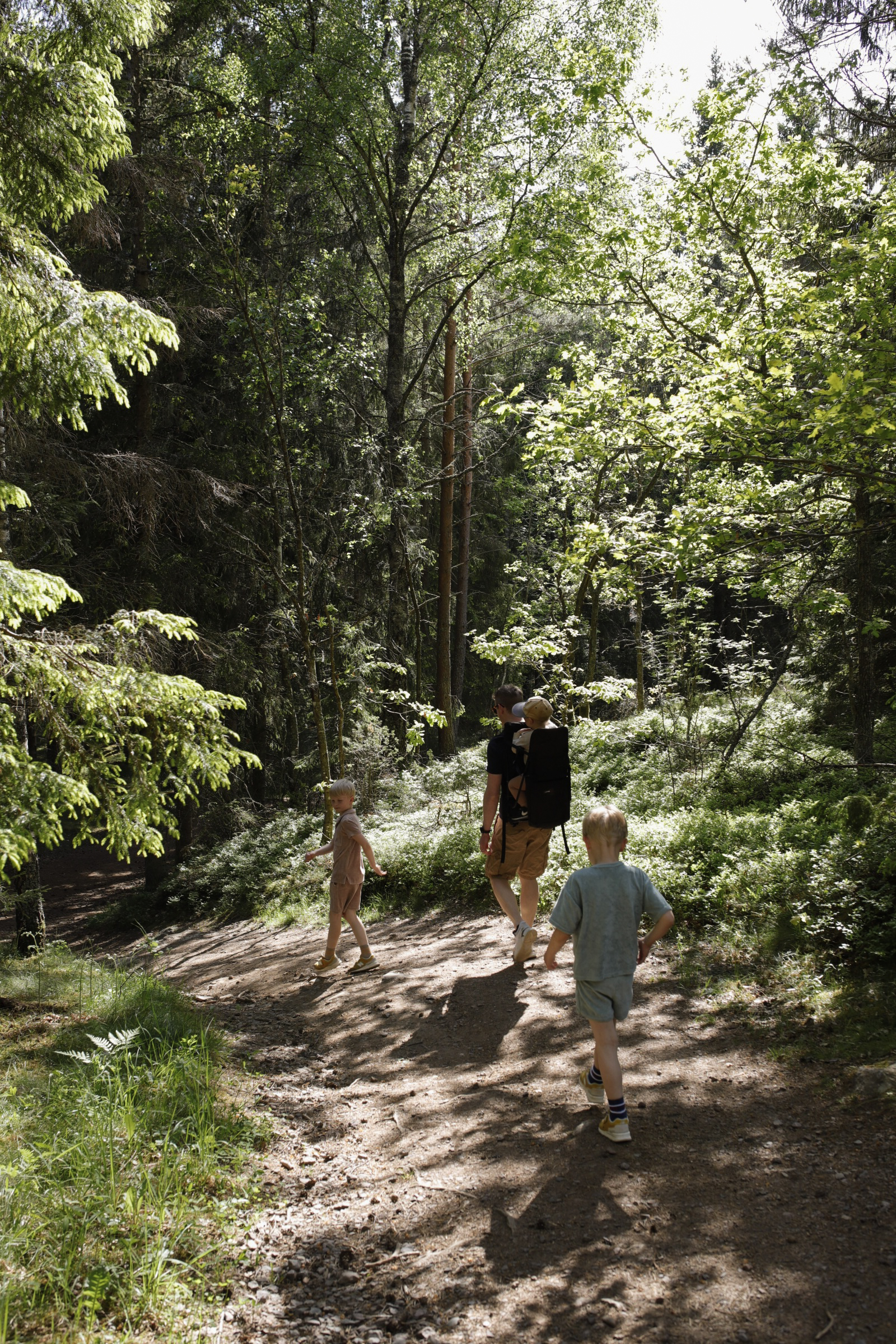 Linnéas man och barn vandrar i skogen. 
