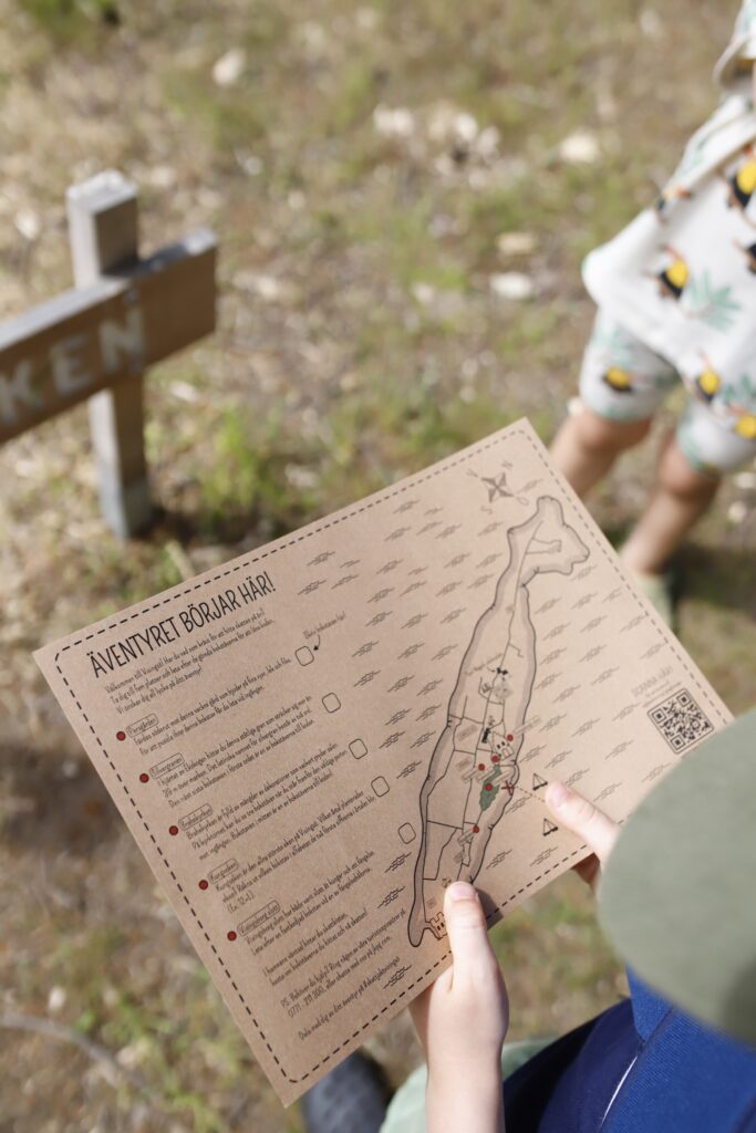 Person håller upp en karta med rubriken "äventyret börjar gär!"