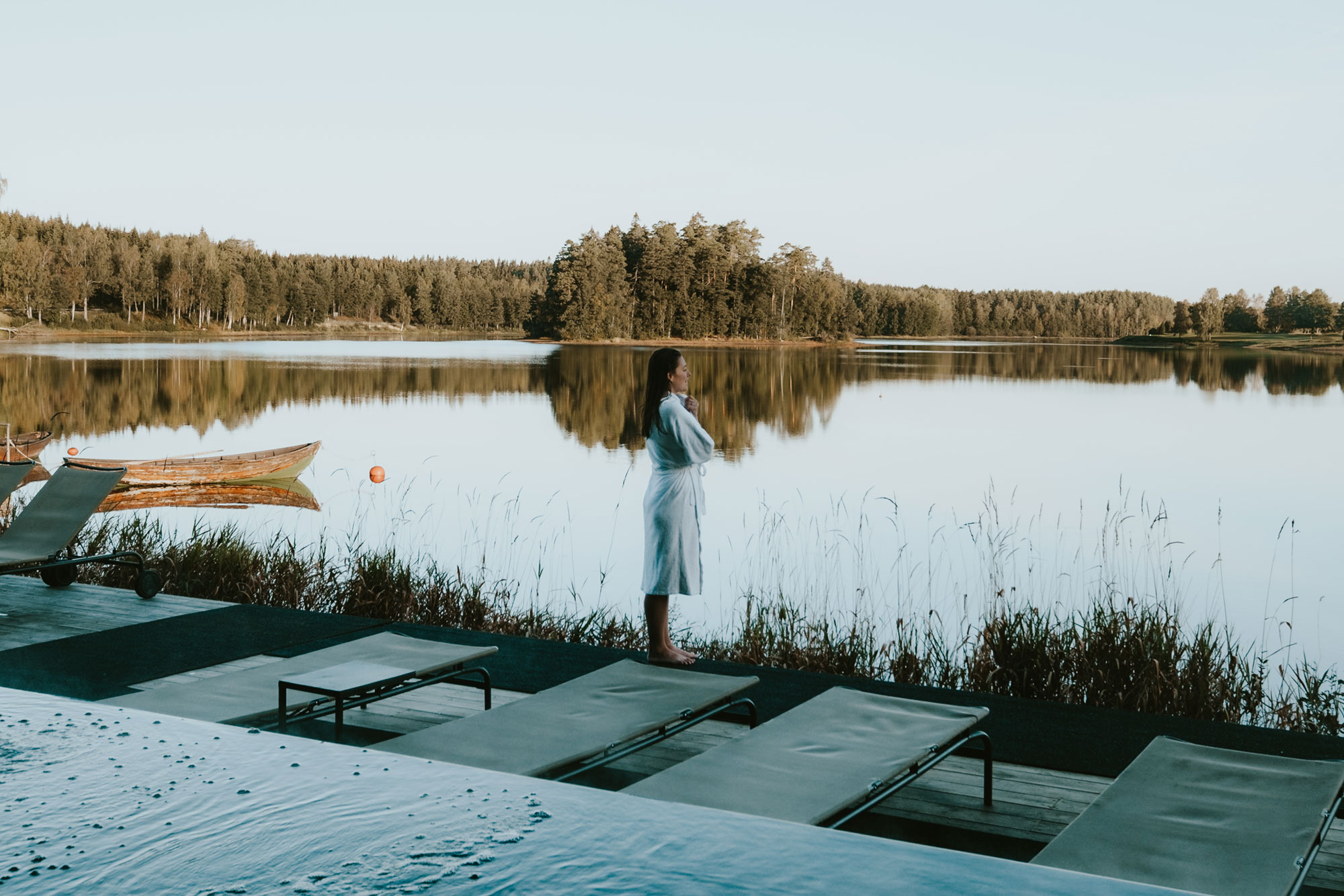 Kvinna i badrock tittar ut över insjö i Småland