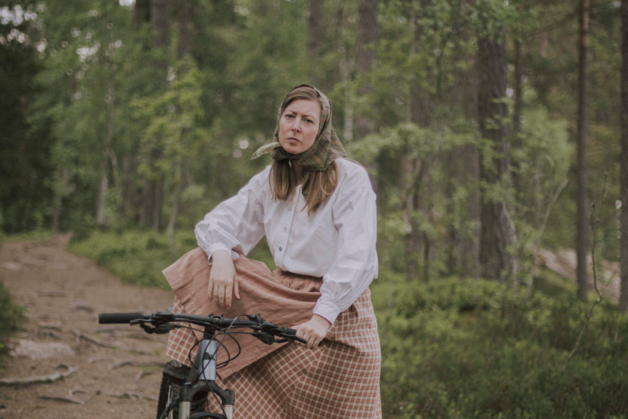 Bild på en sittandes Kristina på en cykel i skogen.